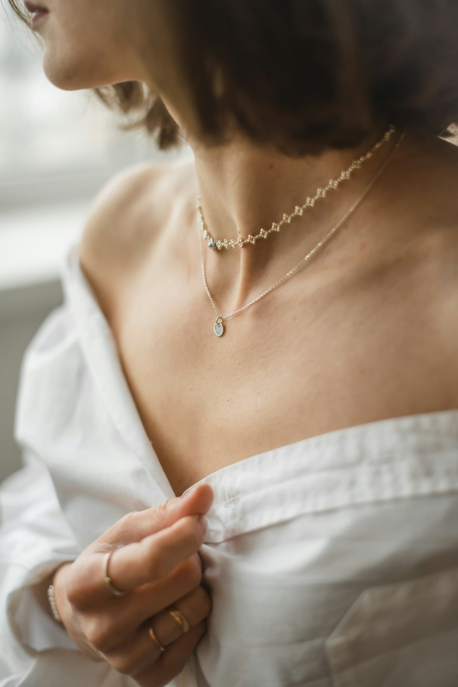 A client wearing delicate custom jewelry in soft daylight